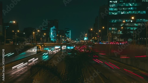 Street traffic in Lima at night. Office skyscraper buildings and busy traffic on highway road with blurred cars light trails. Via expresa, Lima Peru