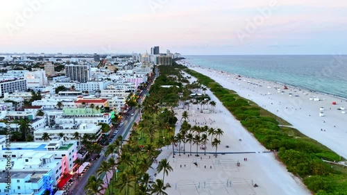 Aerial drone zoom out view of South Beach in Miami, Ocean Drive street at sunset, buildings, palm trees. photo