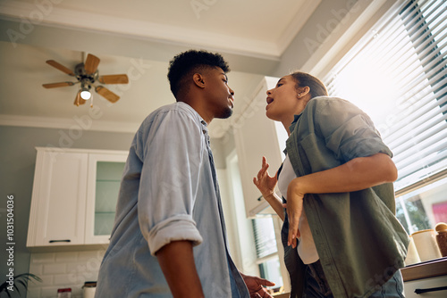 Below view of multiracial couple having fun while dancing in kitchen.