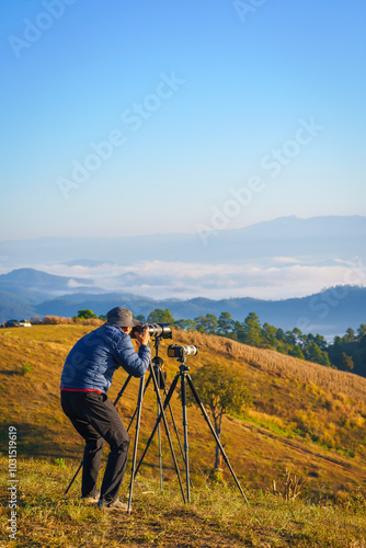 Asian man takes a photo of the beautiful natural scenery of the sea of mist in the morning at Doi Ba Lu Kho Mountain View Point, Mae Chaem, Chiang Mai, Northern Thailand. photo