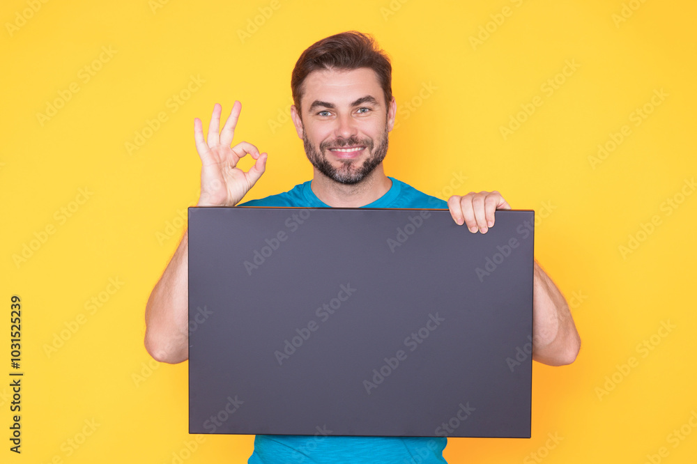 Handsome man holding empty board and pointing ok on studio background. Guy showing blank signboard with copyspace. Idea and offer. Your advertisement. Blank advertising board with empty space, mockup. Handsome man holding empty board and pointing ok on studio background. Guy showing blank signboard with copyspace. Idea and offer. Your advertisement. Blank advertising board with empty space, mockup.