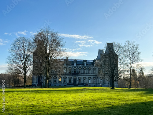 Obraz na plátně Historic mansion surrounded by lush green lawn and trees under a clear blue sky