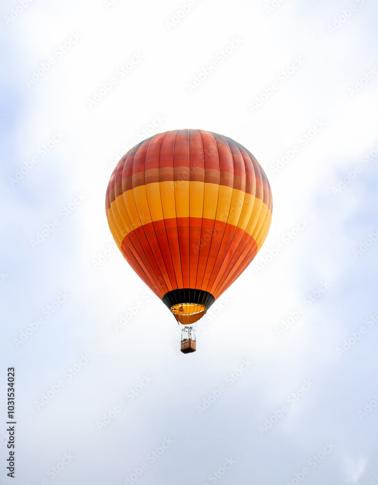 Fototapeta premium A vibrant orange and yellow hot air balloon ascends against a clear white sky.