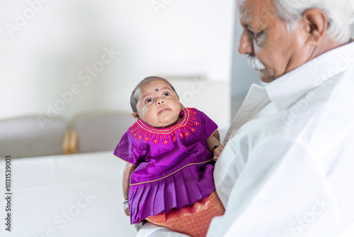 ndian family spending time together, wearing traditional and casual outfits with a baby, a young girl, and grandparents in a high-rise apartment in Kuala Lumpur, Malaysia. photo