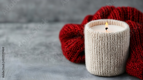 Cozy candle wrapped in knitted sweater with red scarf photo