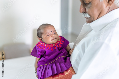 ndian family spending time together, wearing traditional and casual outfits with a baby, a young girl, and grandparents in a high-rise apartment in Kuala Lumpur, Malaysia. photo