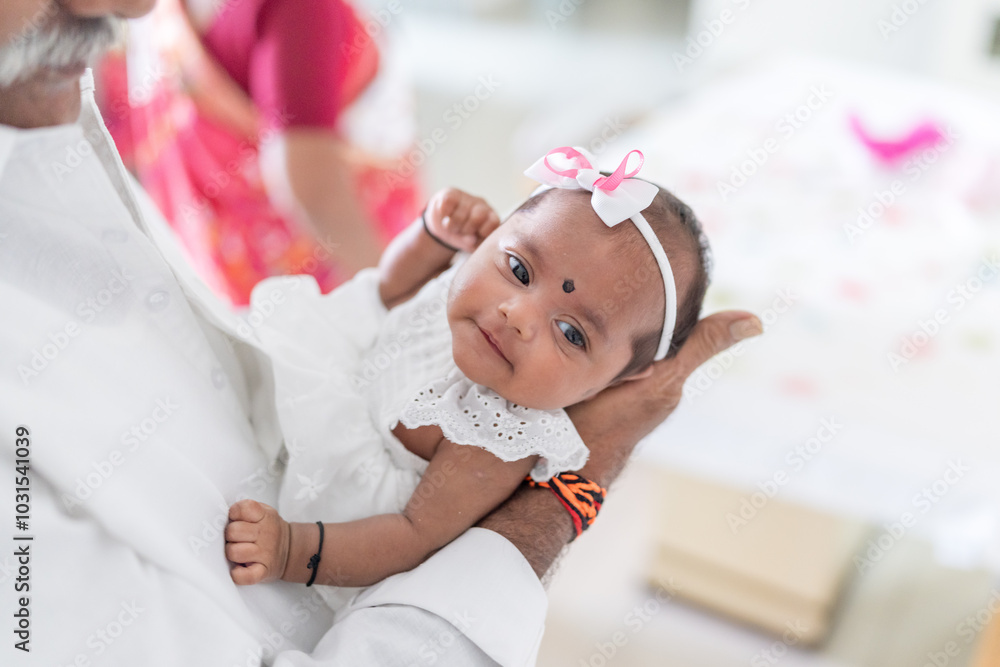 Fototapeta ndian family spending time together, wearing traditional and casual outfits with a baby, a young girl, and grandparents in a high-rise apartment in Kuala Lumpur, Malaysia