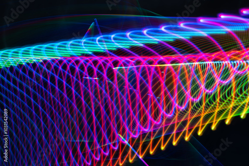 A colorful, swirling line of light that appears to be moving. The colors are bright and vibrant, creating a sense of energy and excitement. The line seems to be moving in a spiral pattern