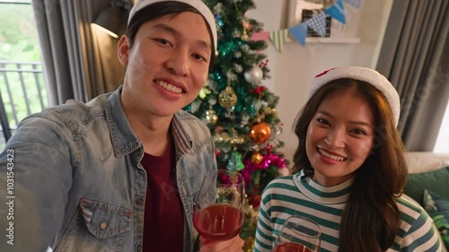 happy christmas eve thanksgiving holiday asian marry couple smartphone selfie videl calling or online vlog influencer show home decorate with xmas ornament decoration tree smiling cheerful at home photo