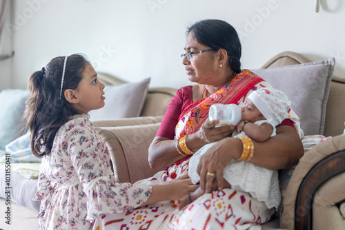 ndian family spending time together, wearing traditional and casual outfits with a baby, a young girl, and grandparents in a high-rise apartment in Kuala Lumpur, Malaysia. photo