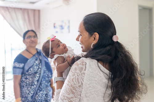 ndian family spending time together, wearing traditional and casual outfits with a baby, a young girl, and grandparents in a high-rise apartment in Kuala Lumpur, Malaysia. photo