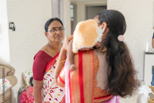 ndian family spending time together, wearing traditional and casual outfits with a baby, a young girl, and grandparents in a high-rise apartment in Kuala Lumpur, Malaysia. photo