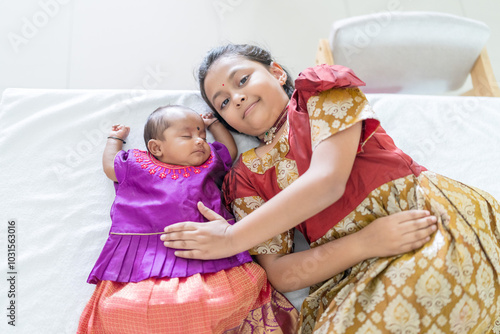 ndian family spending time together, wearing traditional and casual outfits with a baby, a young girl, and grandparents in a high-rise apartment in Kuala Lumpur, Malaysia. photo