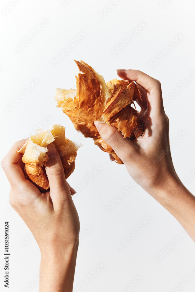 Fotografie Two hands holding a bitten croissant on white background