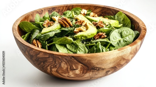 A rustic wooden salad bowl overflowing with a garden-fresh salad, featuring spinach, avocado, and walnuts, set against a bright white backdrop.