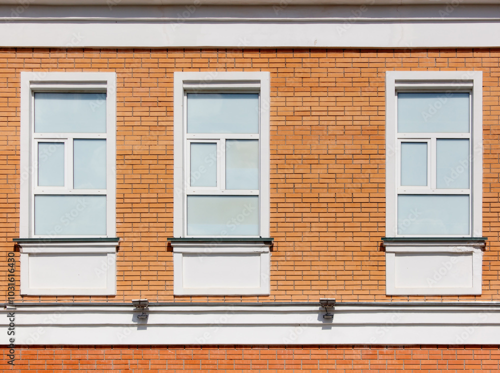 Three windows on a brick building with white trim Three windows on a brick building with white trim