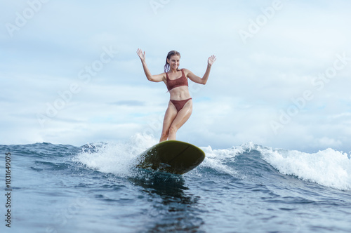 Happy woman longboarding surfing on small wave photo