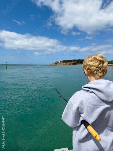 Boy fishing on pier with a wide view of the sea at Barwon Heads photo