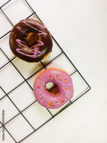 top view of two donu isolated on a white background. chocolate donuts with purple cream and purple donuts with colorful sprinkles. sweet and delicious food. Vertical photo
 photo