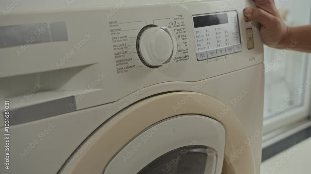 Cropped shot of anonymous person setting cycle of washing machine at home Cropped shot of anonymous person setting cycle of washing machine at home