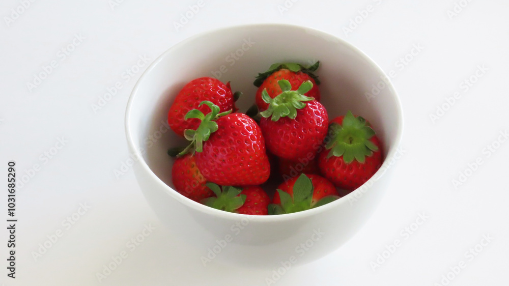 A white bowl full of red ripe fresh strawberries