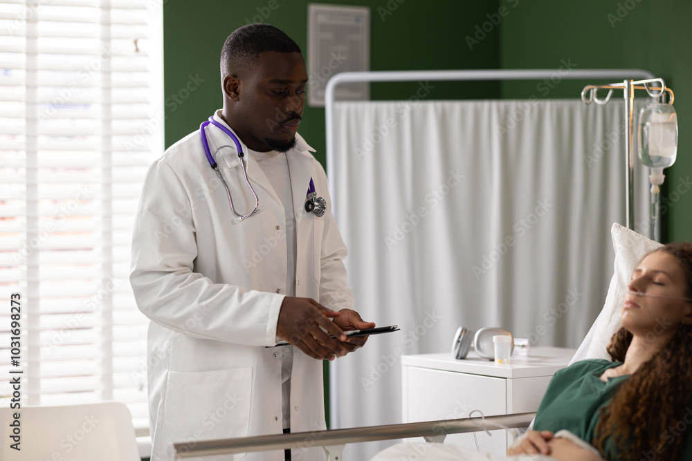 Obraz premium Doctor stands next to the red-haired patient's bed, tablet in hand. The girl, with a catheter, gets a regular checkup with a touch of simplicity.