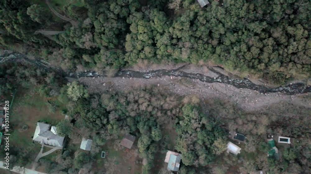 Top-down aerial view of houses in a mountain neighborhood with a beautiful rocky river flowing through. Top-down aerial view of houses in a mountain neighborhood with a beautiful rocky river flowing through.