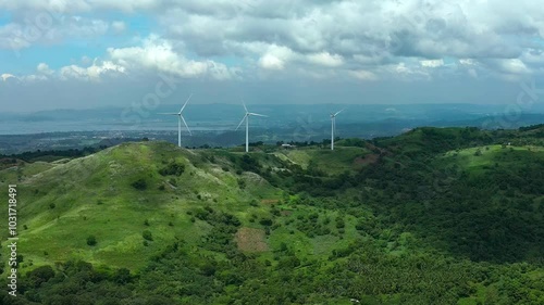 Pililla Wind Mills between green mountains of Philippines Rizal. Cloudy day on asian island. Production of eco friendly energy with wind. Drone wide shot. photo