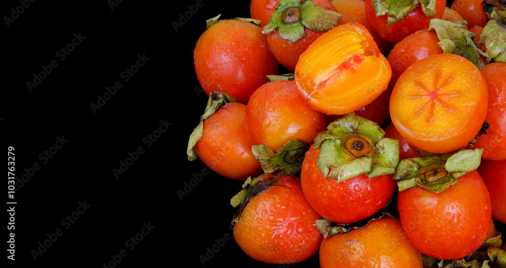 Many wet persimmon fruits isolated on black background. Copy space for text. Many wet persimmon fruits isolated on black background. Copy space for text.