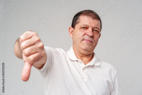 A middle-aged man expressing disapproval with a thumbs-down gesture i