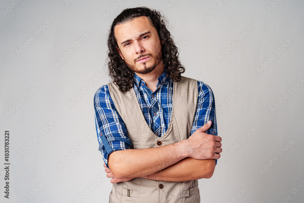 Obraz premium A confident young man with curly hair poses against a neutral backdrop