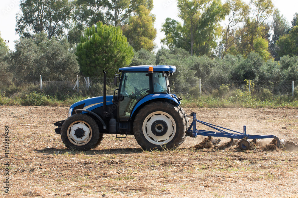 A tractor starts to pilow a crop field to prepare seeding winter wheat in autumn A tractor starts to pilow a crop field to prepare seeding winter wheat in autumn