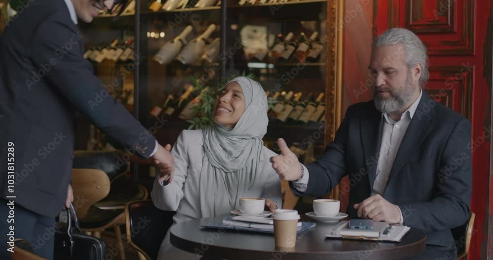 Diverse group of businesspeople meeting in cafe shaking hands and talking sitting around table together. Collaboration and negotiation concept. Diverse group of businesspeople meeting in cafe shaking hands and talking sitting around table together. Collaboration and negotiation concept.