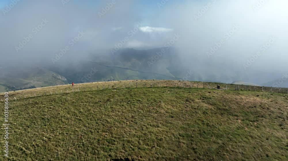 Aerial drone view of a man climbing a green mountain in beautiful sunny summer day in the Pyrene mountains, France Aerial drone view of a man climbing a green mountain in beautiful sunny summer day in the Pyrene mountains, France