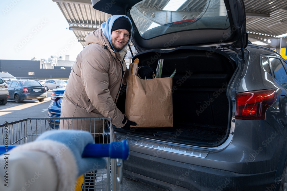 Man Loading Groceries into Car Trunk