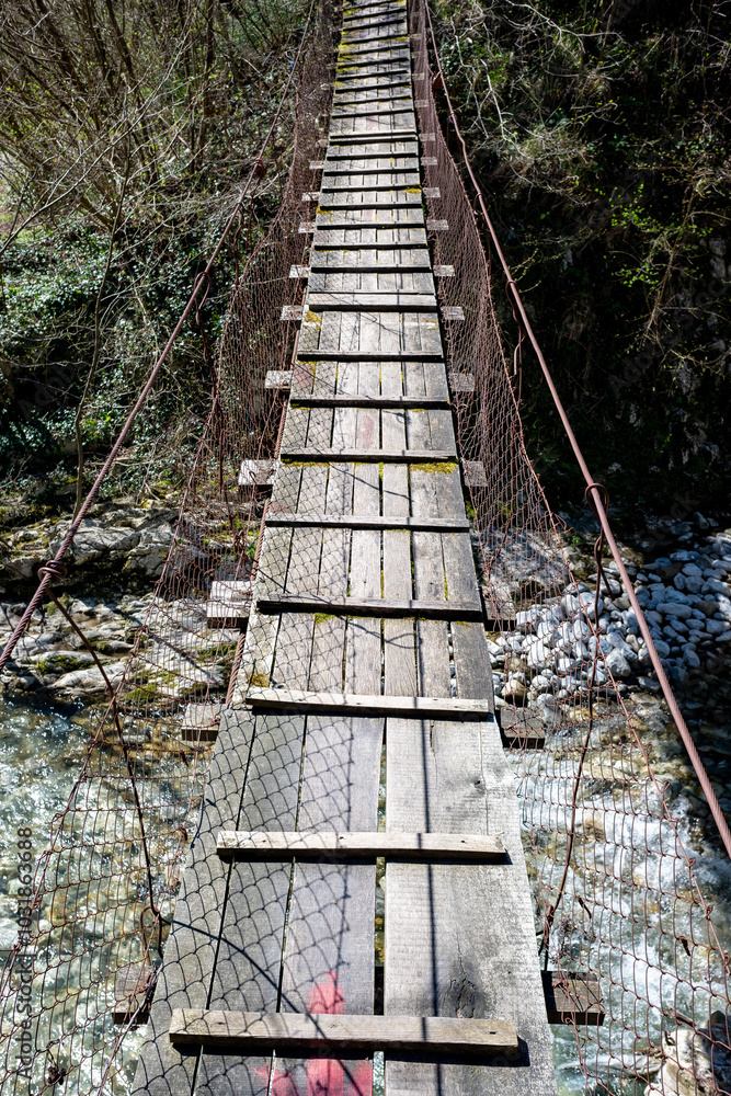 A wooden bridge with a metal chain link fence A wooden bridge with a metal chain link fence