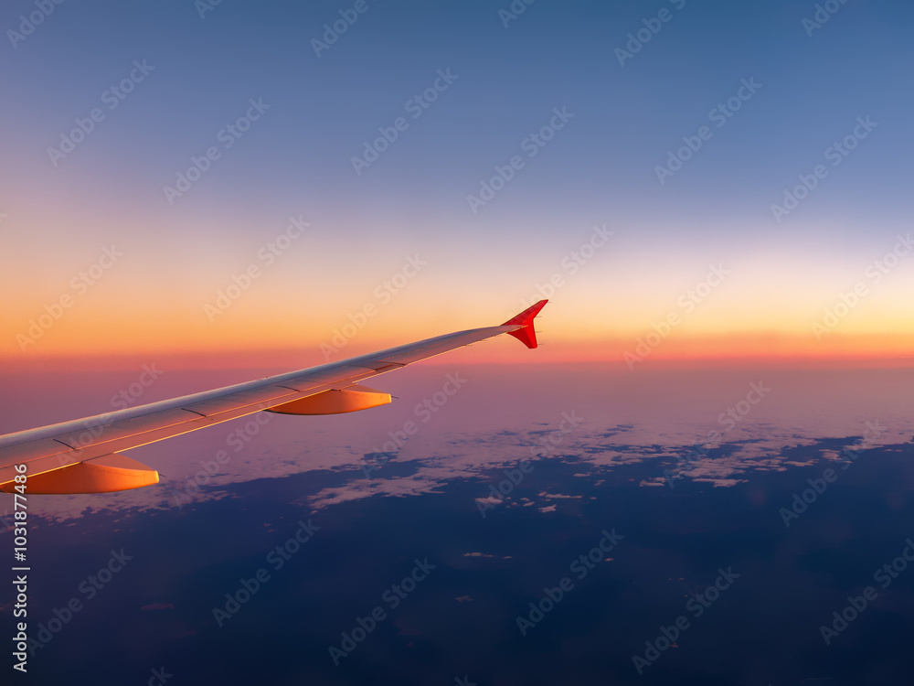 Aerial view from an airplane window at sunset, featuring a colorful horizon and the plane's wing, perfect for travel, aviation, and scenic content Aerial view from an airplane window at sunset, featuring a colorful horizon and the plane's wing, perfect for travel, aviation, and scenic content