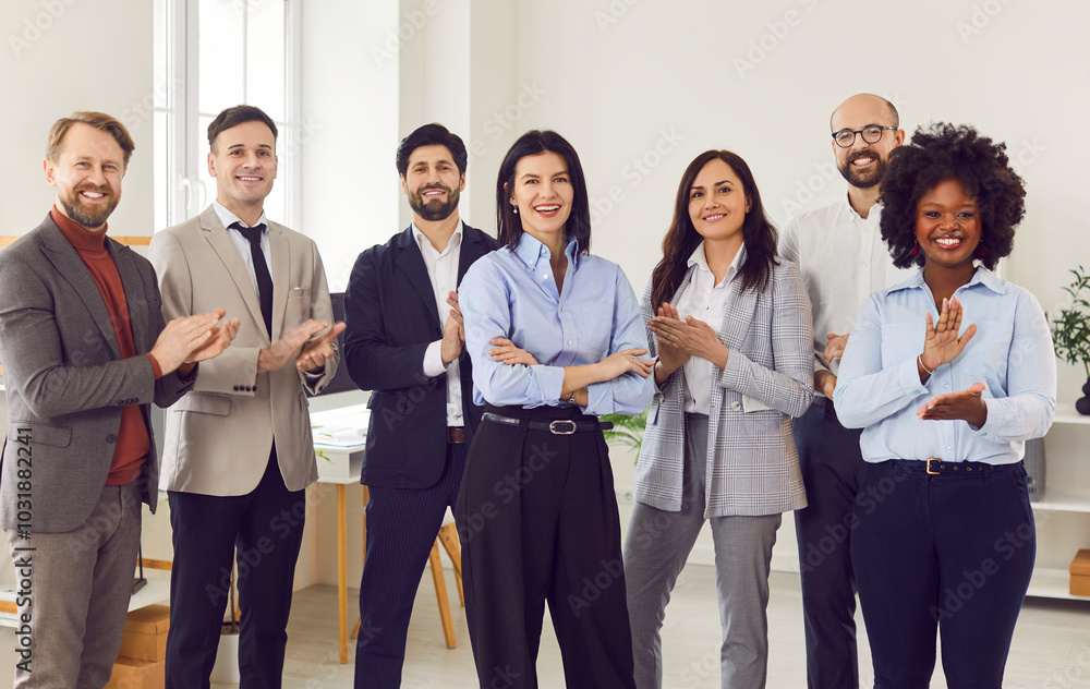 Group portrait of happy multiethnic united team in office applauding welcoming new coworker, successful employees standing together meeting in workspace, business colleagues looking at camera smiling Group portrait of happy multiethnic united team in office applauding welcoming new coworker, successful employees standing together meeting in workspace, business colleagues looking at camera smiling