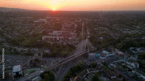 Aerial view of Dundrum cable-stayed bridge with the luas train passing by and Dublin mountains in the background during a gold sunset time - End of summer in Ireland - Dublin, Ireland photo