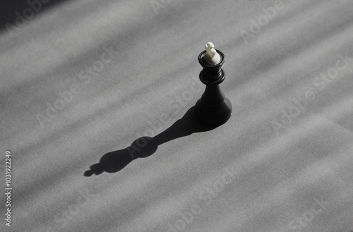 Photography A black chess king in soft sunlight and black shadow on a gray background, a lone candidate, career sunset, political loneliness, the fragility of power and the need for protection