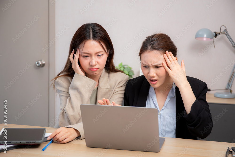 Two businesswoman stress and frustrated while working on laptop computer in office, two business woman serious and problem about project, expression and trouble, business and finance with problem. Two businesswoman stress and frustrated while working on laptop computer in office, two business woman serious and problem about project, expression and trouble, business and finance with problem.