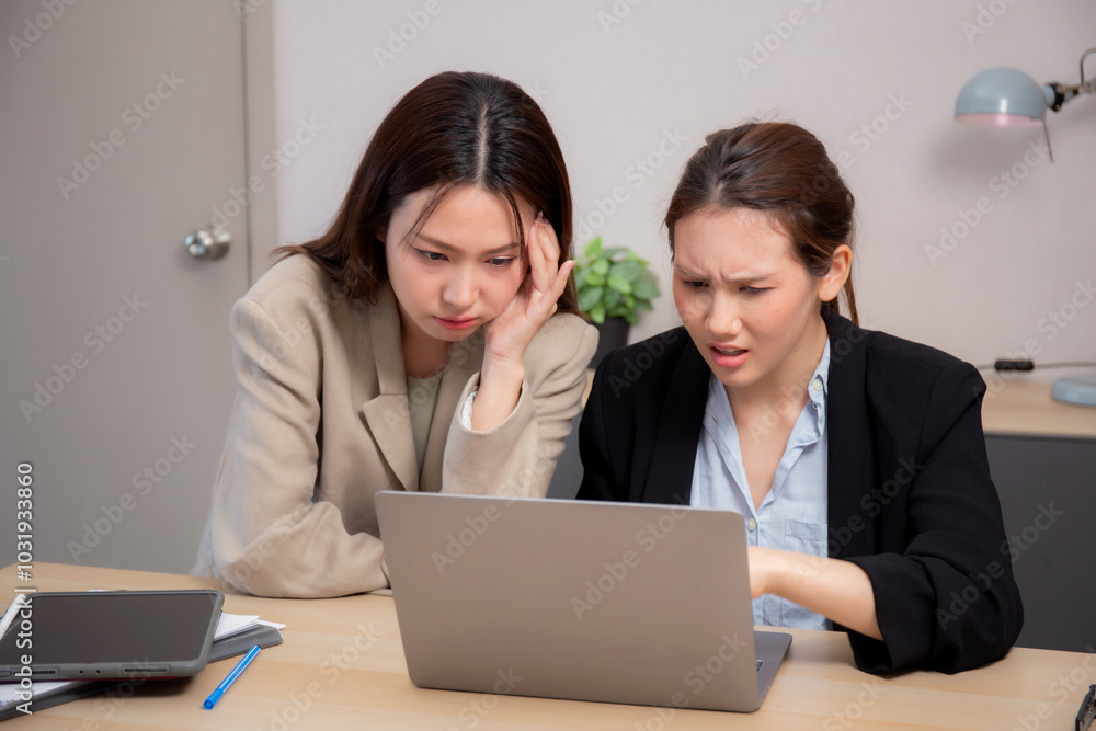 Two businesswoman stress and frustrated while working on laptop computer in office, two business woman serious and problem about project, expression and trouble, business and finance with problem. Two businesswoman stress and frustrated while working on laptop computer in office, two business woman serious and problem about project, expression and trouble, business and finance with problem.