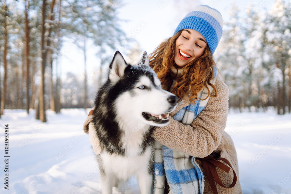 A young woman in warm clothes walking with her husky dog in a picturesque snowy outdoor. Playing with pets. Friendship concept. A young woman in warm clothes walking with her husky dog in a picturesque snowy outdoor. Playing with pets. Friendship concept.