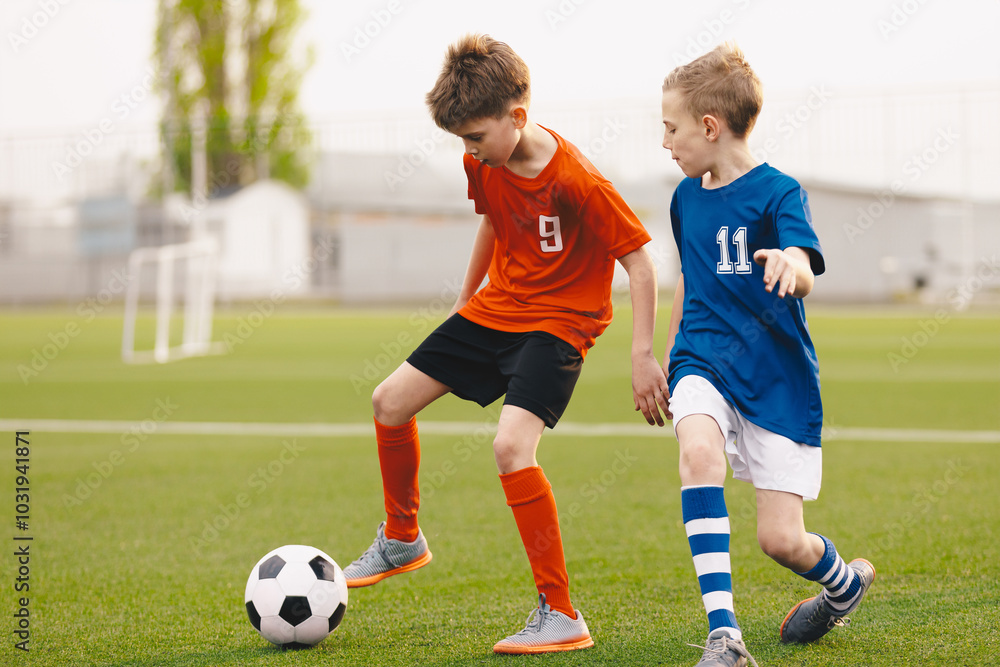 Obraz premium Football soccer match for children. Boys in blue and red shirts playing football game on school tournament. Dynamic, action picture of kids competition during playing football. Sport background image