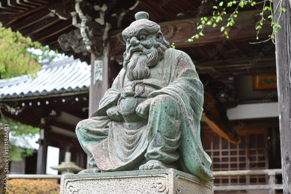 Obraz premium Ancient stone statue of a wise figure at a tranquil temple garden during a serene afternoon