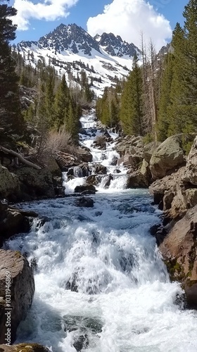 Rushing river flows through rocky terrain under a vibrant blue sky in the mountains