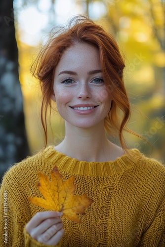 Young woman smiles while holding a maple leaf in a sunny autumn park
