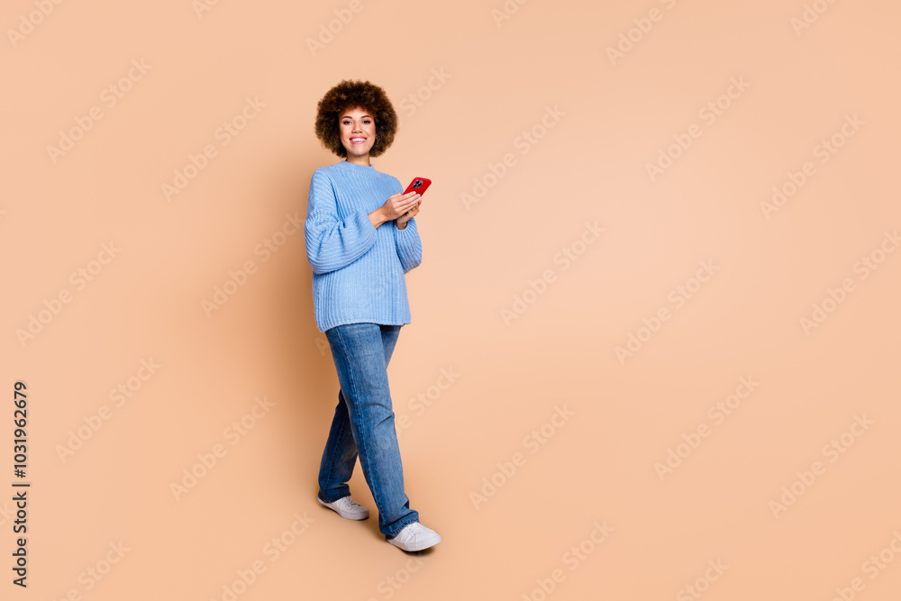 Full size photo of positive cheerful girl dressed blue knit sweater walk with smartphone in hands isolated on pastel color background Full size photo of positive cheerful girl dressed blue knit sweater walk with smartphone in hands isolated on pastel color background