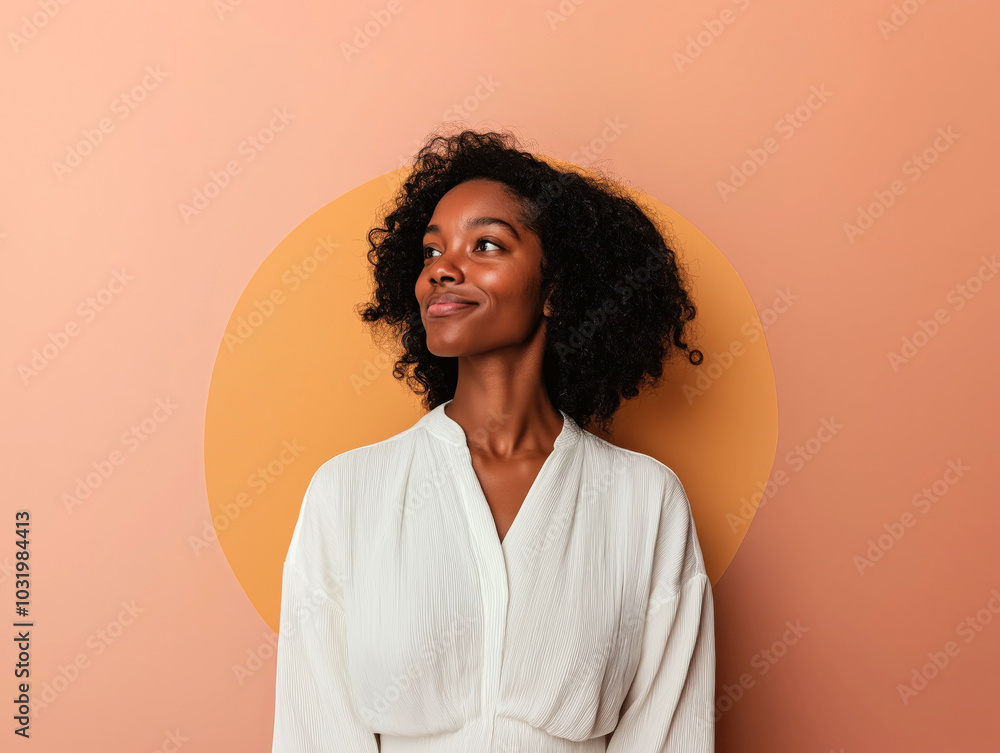Young woman with natural afro hair posing gracefully against a peach-colored wall Young woman with natural afro hair posing gracefully against a peach-colored wall