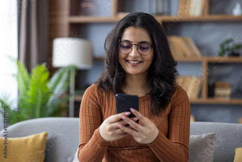 Photography Close-up photo of a young Indian girl at home, holding a mobile phone and smilin
